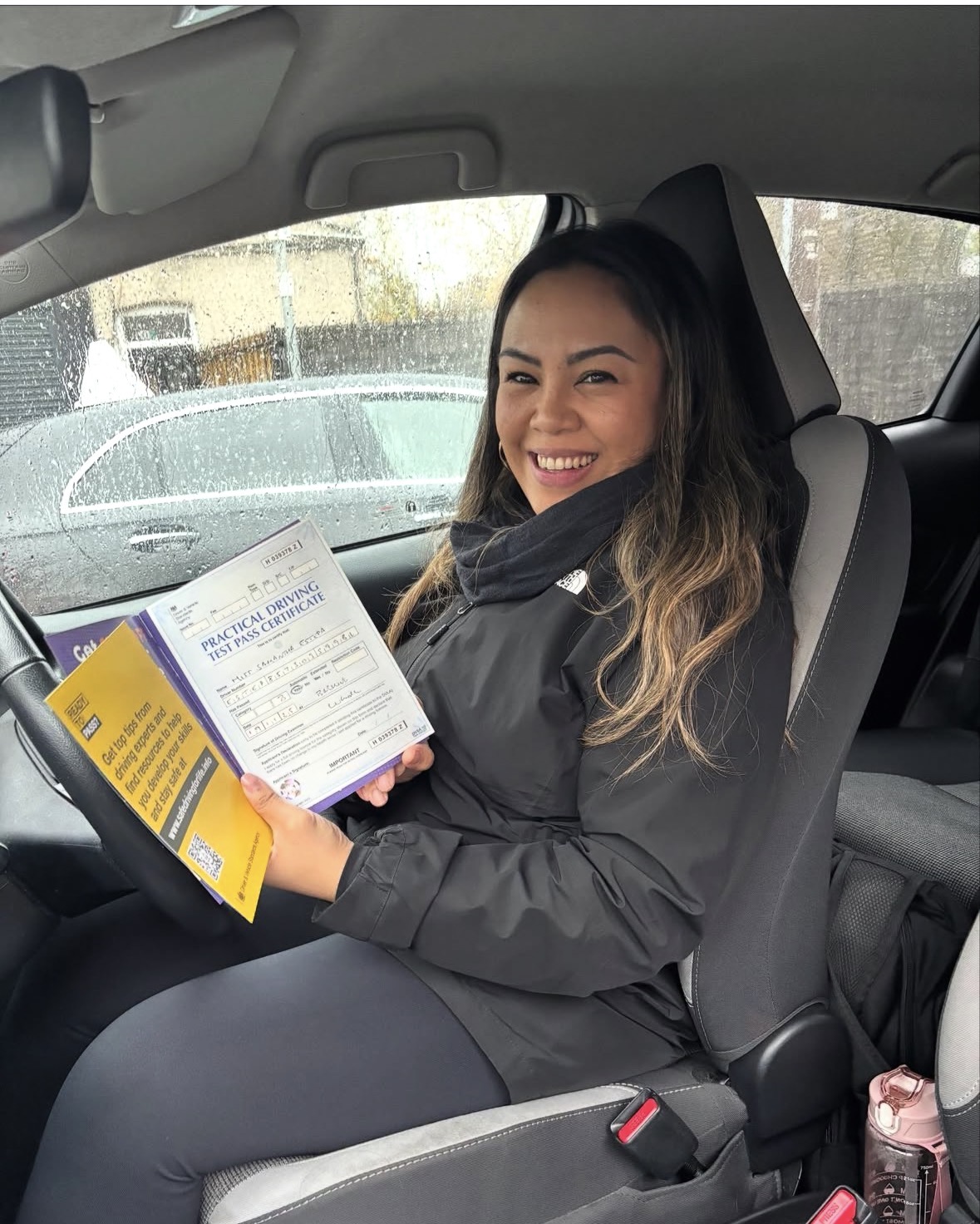 Smiling student holding their driving test pass certificate