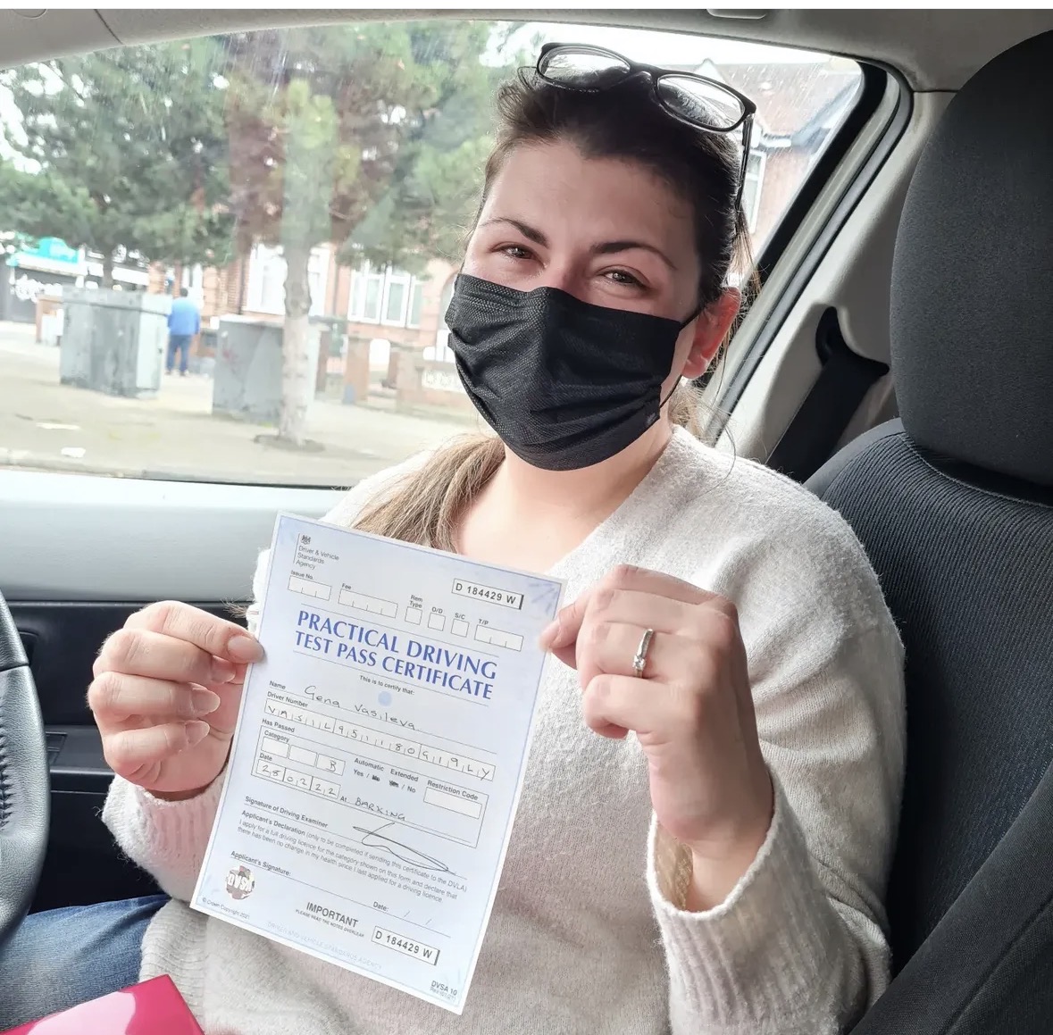 Student proudly showing their practical driving test pass certificate